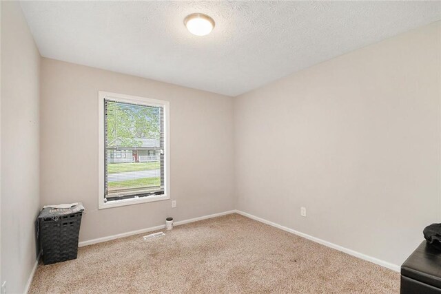 unfurnished room with baseboards, visible vents, carpet flooring, and a textured ceiling