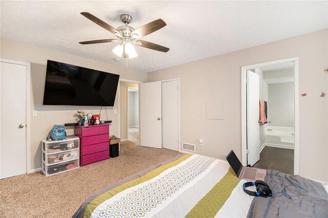 carpeted bedroom with ensuite bathroom, a textured ceiling, visible vents, and ceiling fan