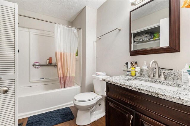 bathroom featuring vanity, shower / tub combo with curtain, toilet, a textured ceiling, and wood finished floors