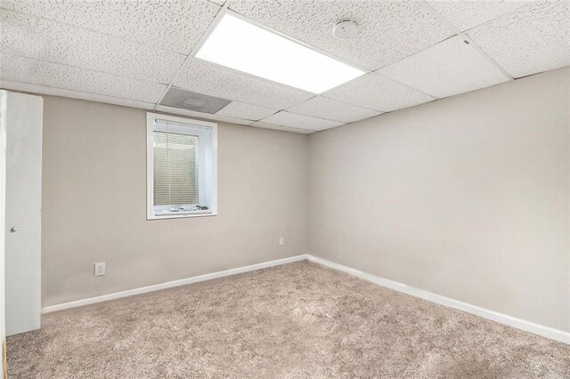carpeted spare room with baseboards and a paneled ceiling