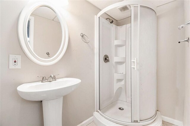 bathroom featuring a stall shower, baseboards, and visible vents