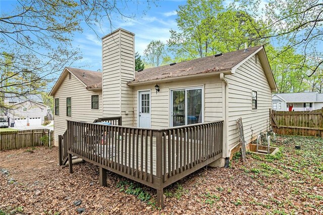 rear view of property with a chimney, a fenced backyard, and a deck