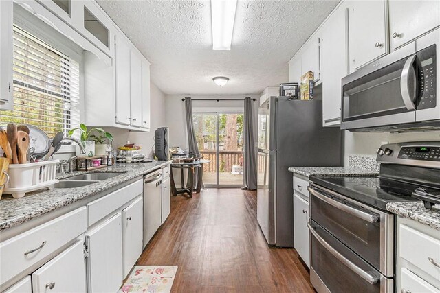 kitchen featuring white cabinets, a sink, stainless steel appliances, and dark wood finished floors