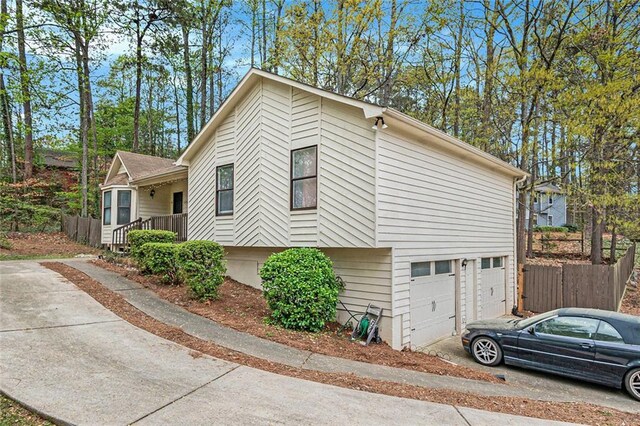 view of side of home with fence, driveway, and an attached garage