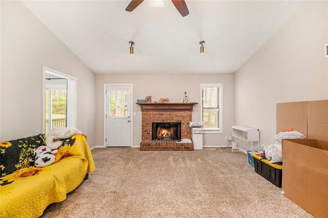 carpeted living area featuring a fireplace, ceiling fan, vaulted ceiling, and plenty of natural light