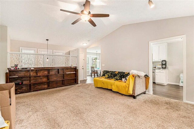 living area with baseboards, carpet floors, vaulted ceiling, and a ceiling fan