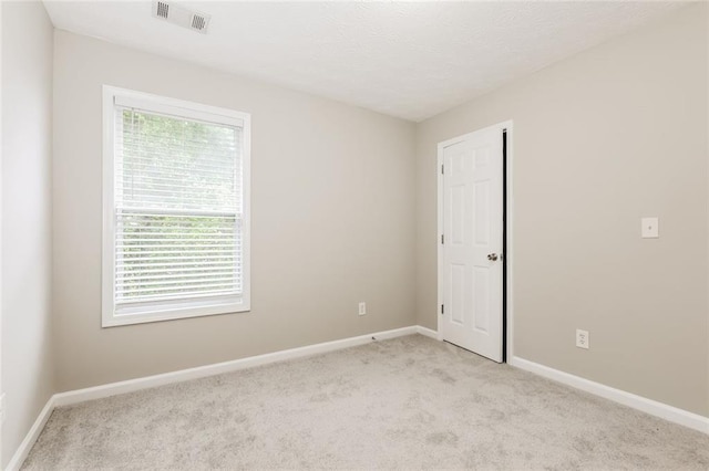 empty room featuring light carpet and baseboards