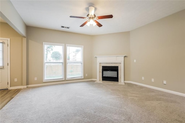 unfurnished living room with carpet, a ceiling fan, a premium fireplace, and baseboards