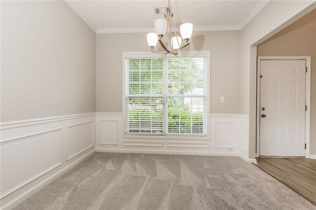 unfurnished dining area with a chandelier, crown molding, a wainscoted wall, a decorative wall, and carpet flooring