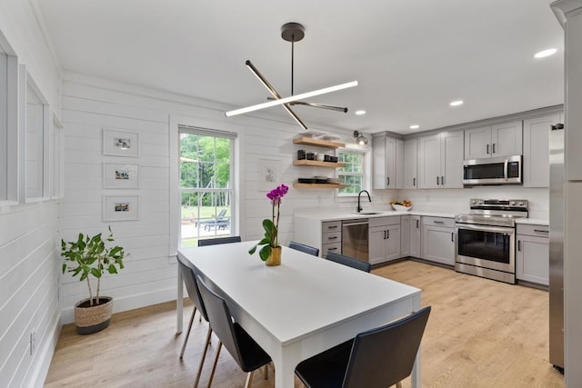 kitchen featuring stainless steel appliances, gray cabinets, open shelves, light countertops, and a sink