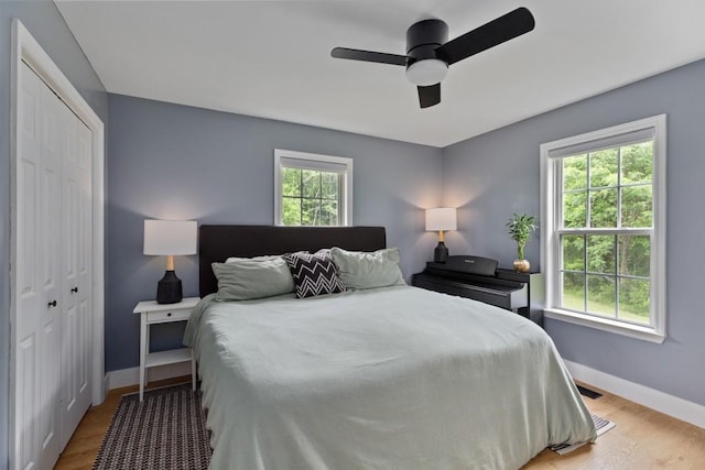 bedroom featuring a closet, baseboards, light wood-type flooring, and ceiling fan
