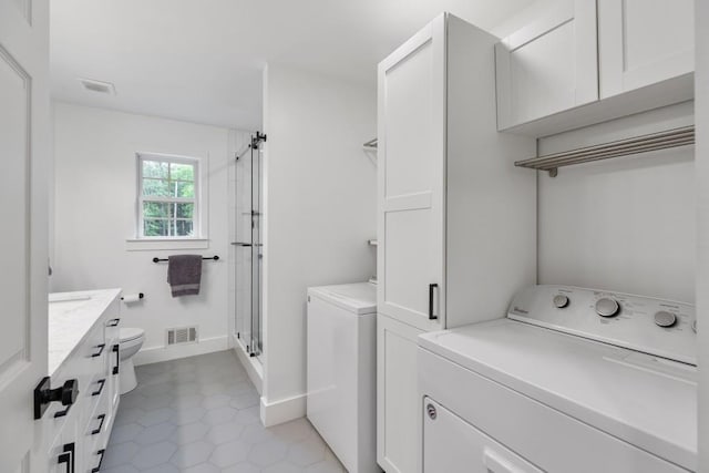 clothes washing area featuring separate washer and dryer, light tile patterned floors, and baseboards