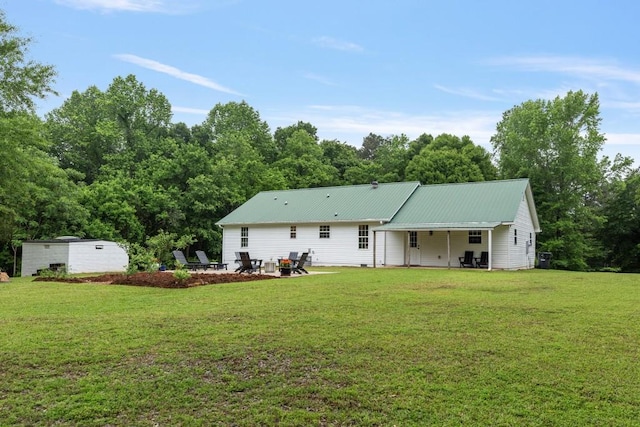 rear view of property with a patio, a yard, and metal roof