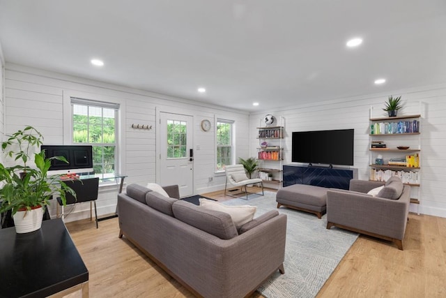 living room with light wood-type flooring, wooden walls, and recessed lighting