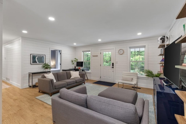 living room with plenty of natural light, light wood-type flooring, wood walls, and recessed lighting