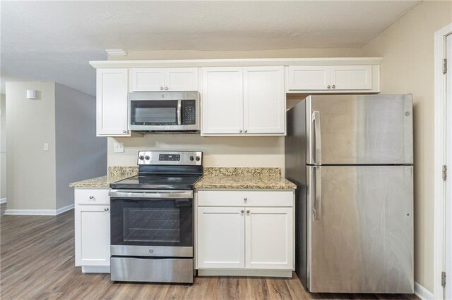 kitchen with white cabinets, light stone countertops, and stainless steel appliances