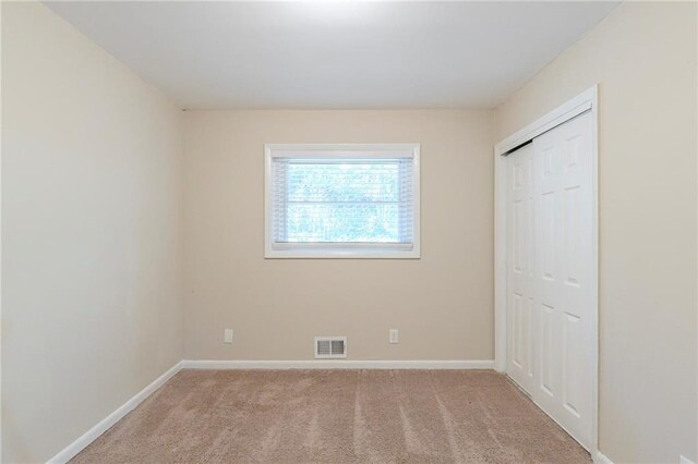 unfurnished bedroom with a closet and light colored carpet