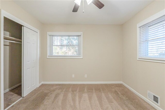 unfurnished bedroom with ceiling fan, light colored carpet, and a closet