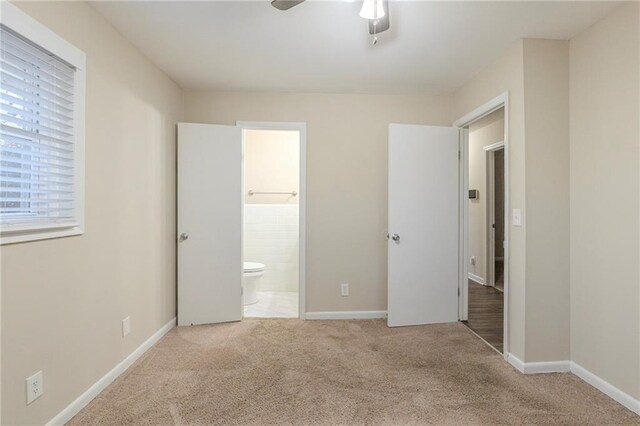 unfurnished bedroom with ceiling fan, light carpet, and ensuite bathroom