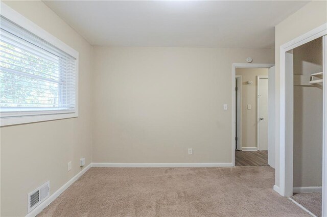 unfurnished bedroom with a closet and light carpet