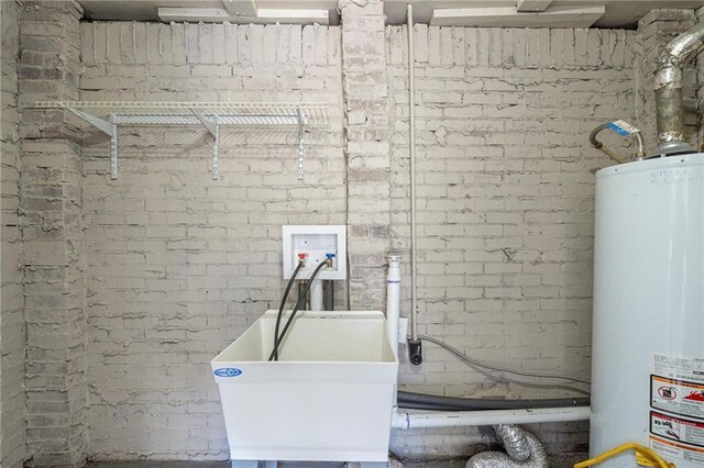 laundry room with sink, hookup for a washing machine, gas water heater, brick wall, and electric dryer hookup