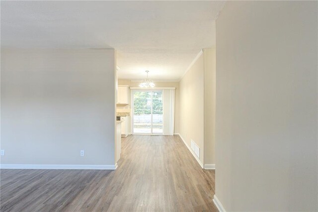 spare room with crown molding, wood-type flooring, and a notable chandelier