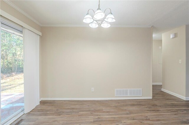 empty room featuring crown molding, an inviting chandelier, and light wood-type flooring