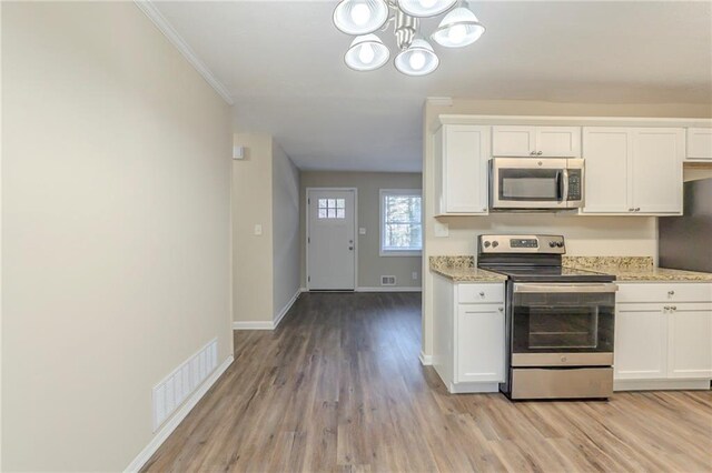 kitchen featuring appliances with stainless steel finishes, light hardwood / wood-style flooring, white cabinets, and a chandelier