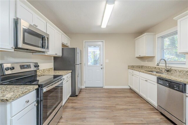 kitchen featuring light stone counters, sink, white cabinets, and stainless steel appliances