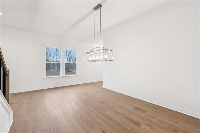 unfurnished dining area with light wood finished floors, baseboards, and an inviting chandelier