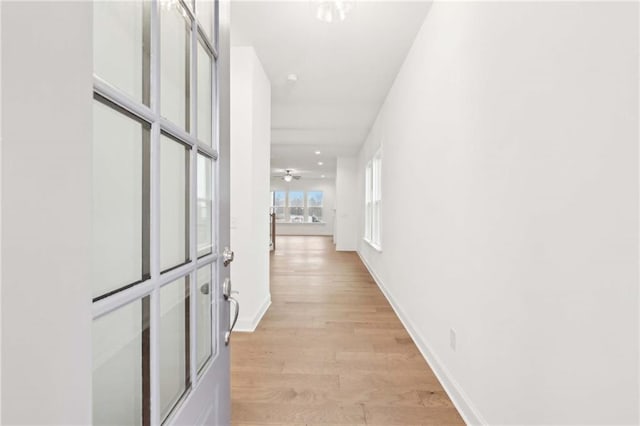 hallway featuring light wood-style floors and baseboards