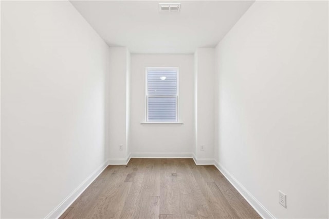 spare room featuring visible vents, baseboards, and wood finished floors