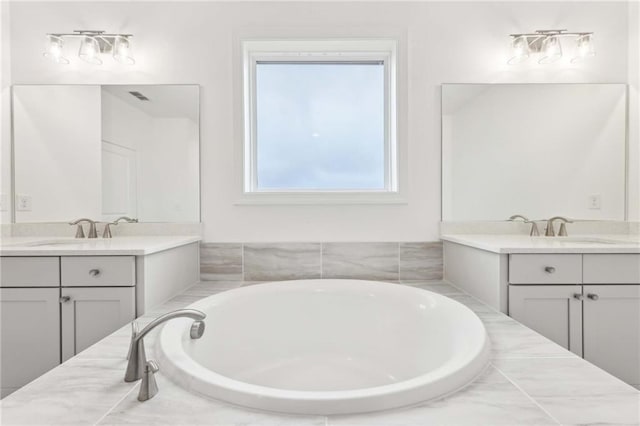 full bathroom with a sink, two vanities, and a garden tub