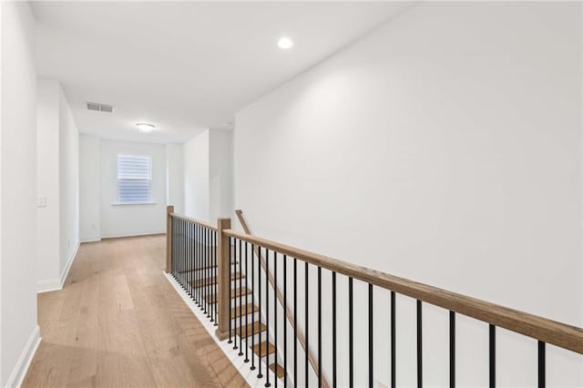 hallway with visible vents, baseboards, an upstairs landing, recessed lighting, and light wood-style flooring