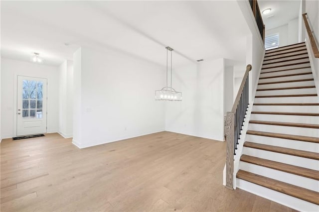 entryway featuring stairs, light wood-style floors, baseboards, and an inviting chandelier