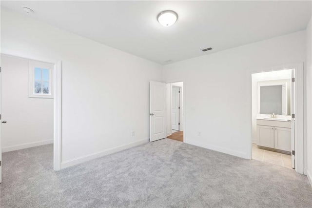 unfurnished bedroom featuring a sink, baseboards, connected bathroom, and light colored carpet