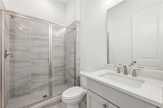 bathroom with toilet, a stall shower, and vanity