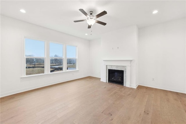 unfurnished living room with light wood finished floors, baseboards, and a ceiling fan