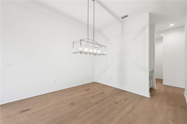 unfurnished dining area featuring baseboards, an inviting chandelier, recessed lighting, visible vents, and wood finished floors