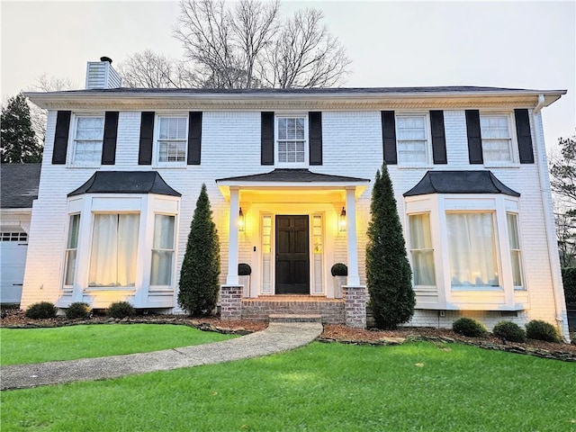 view of front of property featuring a front lawn, brick siding, and a chimney