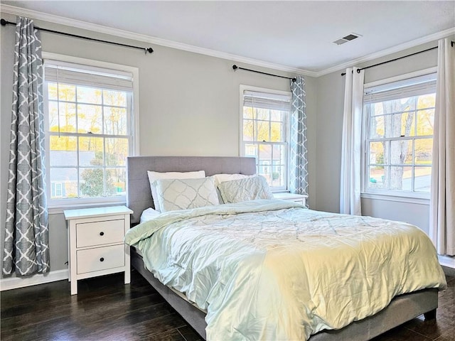 bedroom featuring dark wood-style floors, visible vents, multiple windows, and ornamental molding