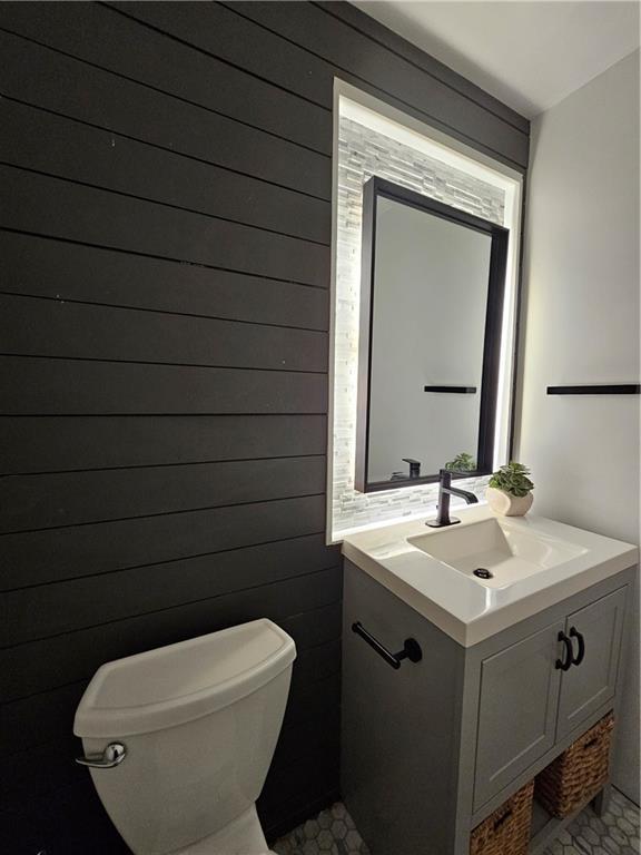 bathroom featuring vanity, toilet, and wood walls