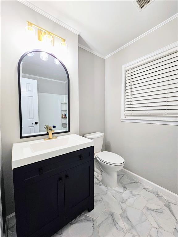 bathroom featuring crown molding, baseboards, toilet, marble finish floor, and vanity