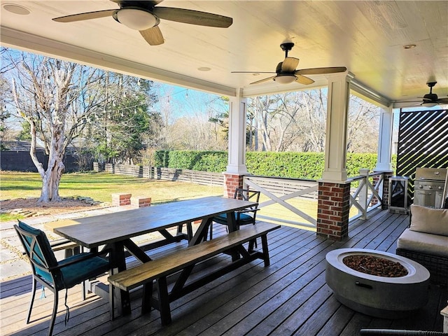 wooden deck with outdoor dining area, a ceiling fan, and a grill