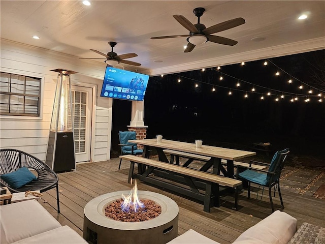 deck with a fire pit, outdoor dining area, and a ceiling fan