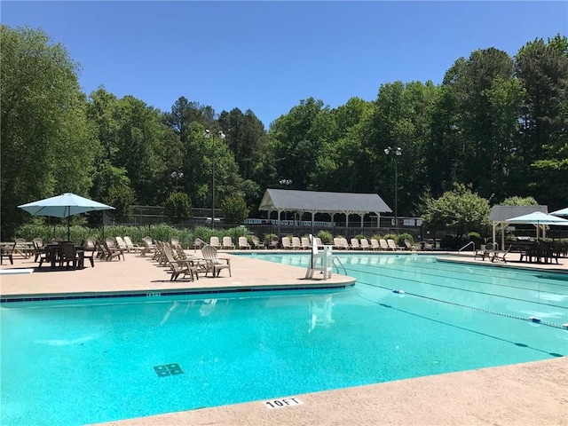 community pool with a patio area and fence