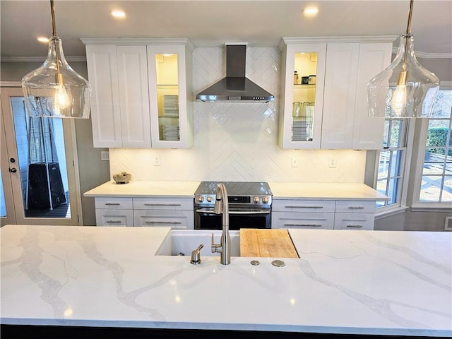 kitchen with tasteful backsplash, white cabinets, stainless steel range with electric cooktop, and wall chimney exhaust hood