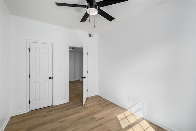 empty room with ceiling fan, wood finished floors, visible vents, and baseboards