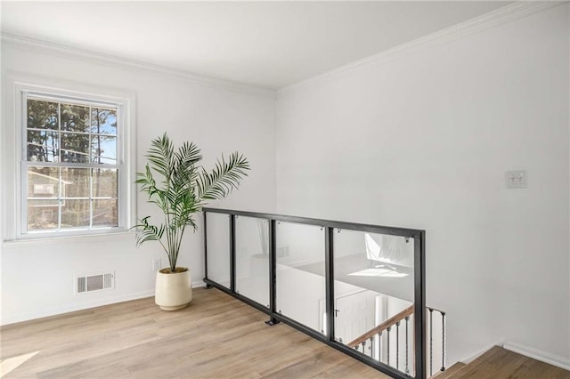 interior space with ornamental molding, baseboards, visible vents, and light wood finished floors