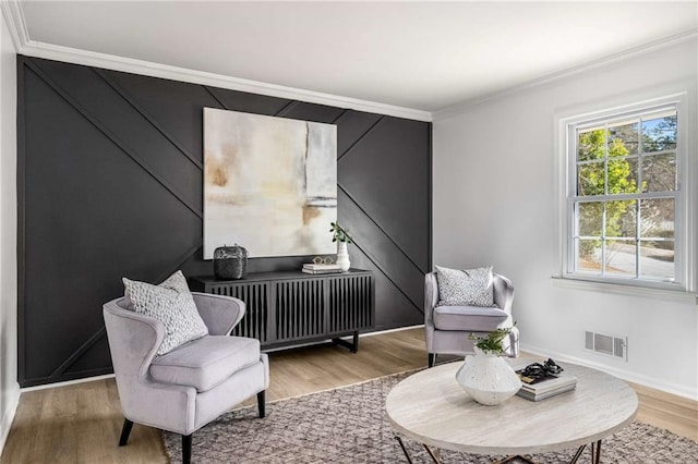 sitting room with baseboards, visible vents, radiator heating unit, ornamental molding, and wood finished floors